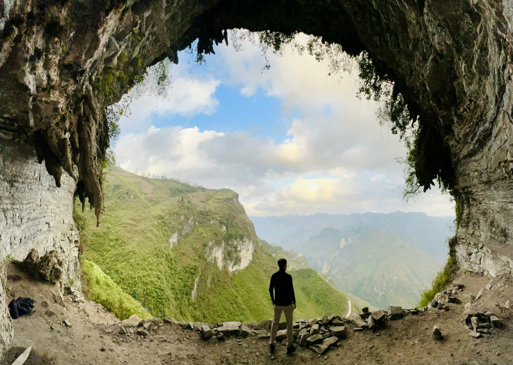 Man Standing in Cave Entrance over Mountains in Vietnam